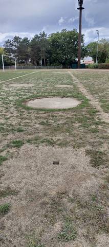 Le cercle de lancer du poids, en béton, gagné par l'herbe sur tout son pourtour — Complexe Sportif de la Croix Jeannette, Bouguenais