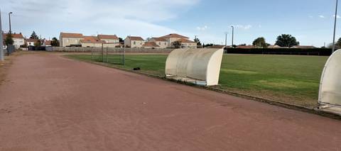 L'anneau en cendrée le long du terrain de football en herbe, abris de touche et pavillons du bourg en fond — Stade Municipal, La Chevrolière