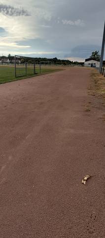 La ligne droite en cendrée, stabilisé rouge-brun sans aucune ligne de couloir, but de football à gauche — Stade Municipal, La Chevrolière