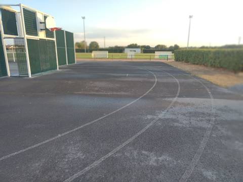 L'anneau en bitume contournant le terrain multisport clos et son panier de basket, le grand stade en cendrée visible au fond — Complexe Sportif Hugues Martin, La Chevrolière