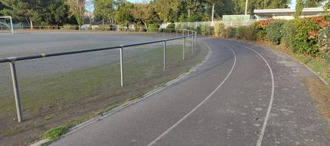 Un virage : l'anneau de bitume, la lice qui le sépare du terrain central en stabilisé, la haie qui le borde à l'extérieur — Plaine de Jeux de la Geraudiere, Nantes