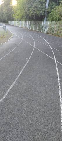 Les lignes de départ décalées, peintes en blanc sur le bitume le long du grillage — Plaine de Jeux de la Geraudiere, Nantes