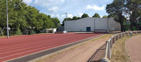 La ligne droite en synthétique, avec les tapis de réception rangés au bout, contre le gymnase — Stade Jean Vincent, Saint-Brevin-les-Pins