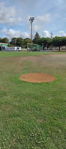 Un cercle de lancer en terre battue posé sur le gazon, la cage en arrière-plan — Stade Jean Vincent, Saint-Brevin-les-Pins