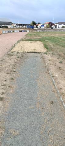 Le couloir d'élan du saut en longueur, enrobé délavé, et son bac de sable colonisé par l'herbe — Complexe Sportif du Parc du Grand Fay, Saint-Père-en-Retz