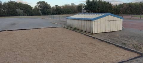 La fosse de saut en longueur, large et bordée d'une bavette caoutchouc noire, l'aire d'élan en enrobé marquée à gauche, et l'abri en bois à toit bleu où est rangé le tapis du sautoir à la perche — Stade Rene Masse, Saint-Sébastien-sur-Loire