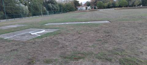 Les deux aires de lancer du poids, dalles béton implantées dans l'herbe hors de l'anneau : cercles peints, lignes de secteur au sol et butoir blanc simplement posé sur la dalle de gauche — Stade Rene Masse, Saint-Sébastien-sur-Loire