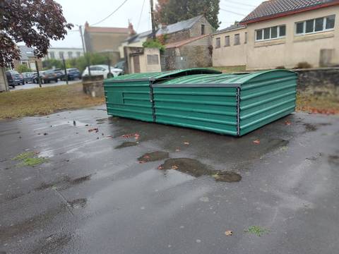 Les deux abris métalliques verts cadenassés où est rangé le tapis du sautoir en hauteur, posés sur une aire en enrobé en bordure de piste — Complexe Vertou Centre, Vertou