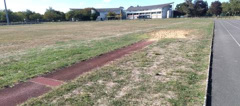 Le sautoir vu depuis la fosse de réception en sable, avec les bâtiments du complexe sportif en arrière-plan — Parc des Sports de la Goducière, Trélazé