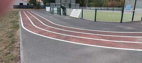 L'anneau longeant la clôture du city-park, bordé d'une pelouse sèche d'un côté et de l'aire de service du complexe de l'autre — Complexe sportif des Grenais, Saint-Philbert-de-Grand-Lieu